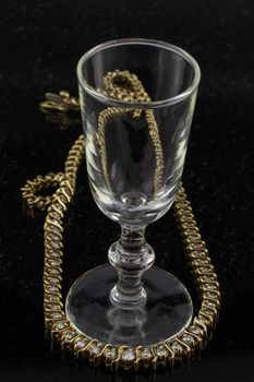 Wine glass with diamond necklace on shiny back surface.