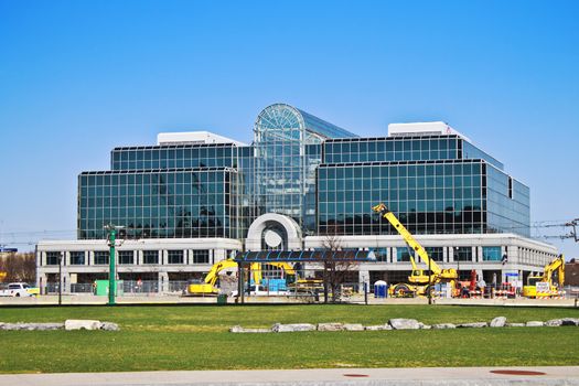 Mirrored glass building in downtown Buffalo. There is a brilliant blue sky behind it and construction machinery in the front. 