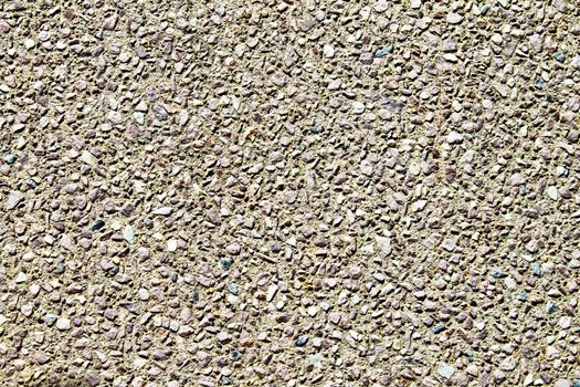 Close up shot of gravel sidewalk. Small pebbles of varying shapes, colors, and sizes are stuck in cement. 