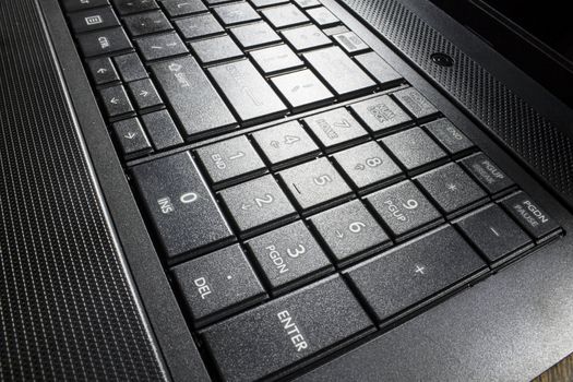 Shining keys of a black laptop. The number pad is highly visible.  
