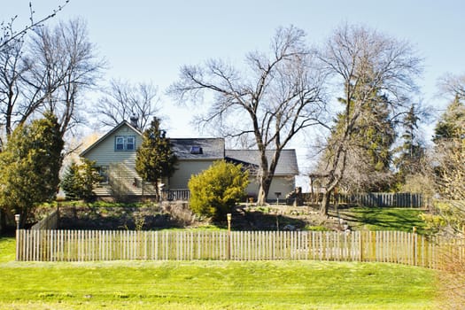 Beautiful country home surrounded by trees. This residence sits on a hill and is surrounded by trees. A wooden fence surrounds the perimeter of the backyard. 