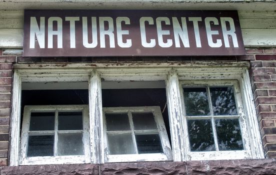 Nature center sign hangs over old style paned windows. 