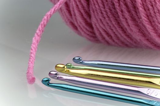 Variety of crochet hooks and ball of pink yarn. 