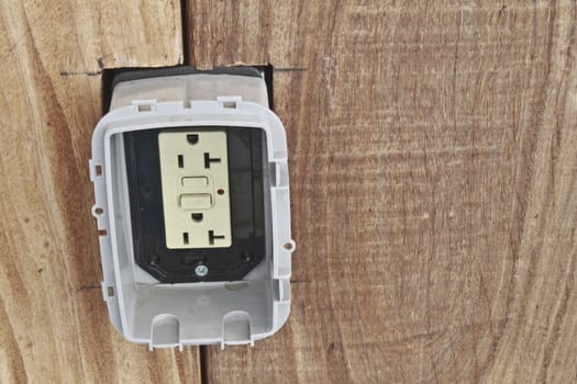 Two plug American empty power outlet with reset buttons built into wood plank wall.