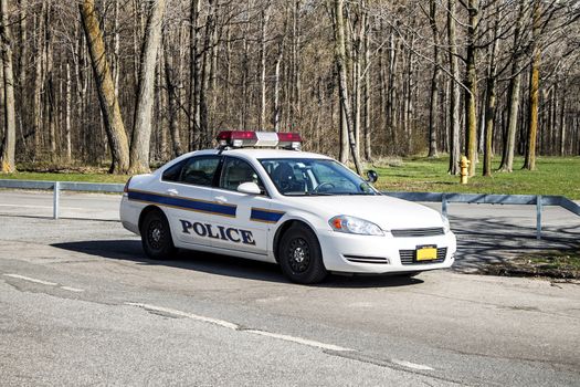 Full view of a modern American police car fully equipped with red emergency lights and reflective stripes.