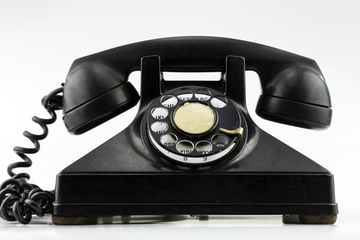 Surface level view of old black rotary dial phone.