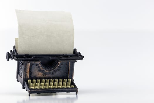 Small antique typewriter with blank paper on roll. Copy space. 