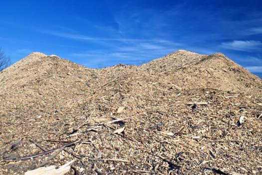 Enormous pile of woodchips from local deforestation. Beautiful blue sky in the background.