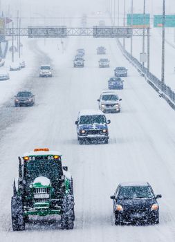 Snowplows and Cars on the Highway During a Snowstorm Winter Day