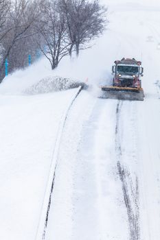 Snowplow Truck Removing the Snow from the Highway during a Cold Snowstorm Winter Day