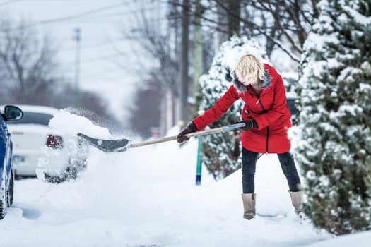 Woman Shoveling her Parking Lot after a Snowstorm