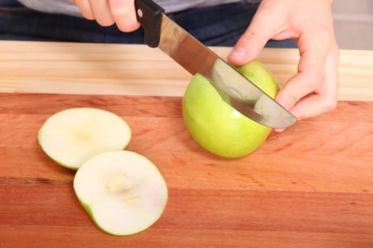 A young adult woman cutting a Apple in the kitchen.