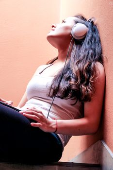 A young woman listening to melancholic Music sitting in the stairway.