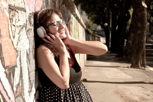 A vintage dressed girl listing to music in a urban environment.