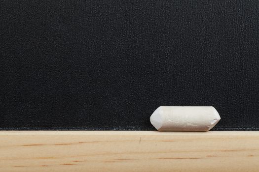 Closeup view of little chalk on the edge of blackboard