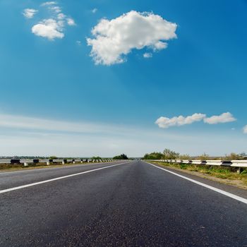 asphalt road to horizon under blue cloudy sky