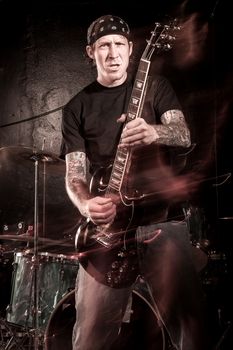 Guitarist playing on a stage. Shot with strobes and slow shutter speed to create lighting atmosphere and blur effects. Heavily filtered.