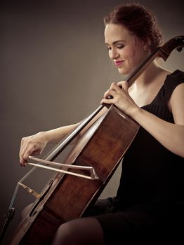 Photo of a beautiful woman playing an old cello.