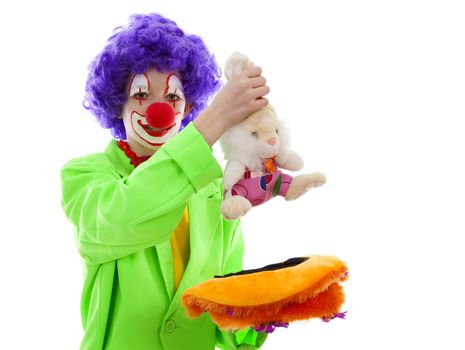 child dressed as funny clown pulling rabbit out of hat over white background