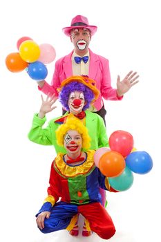 Three people dressed up as colorful funny clowns over white background