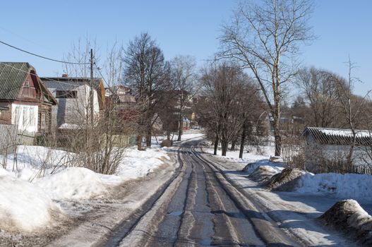 Melting ice on the country road, sunny spring day