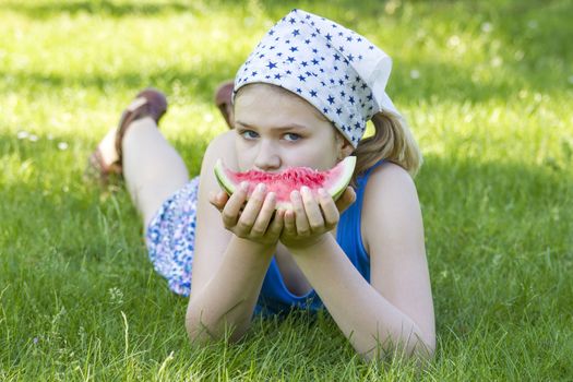 cute little girl eating watermelon on the grass