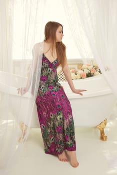 Girl in dress sitting on the edge of the bath