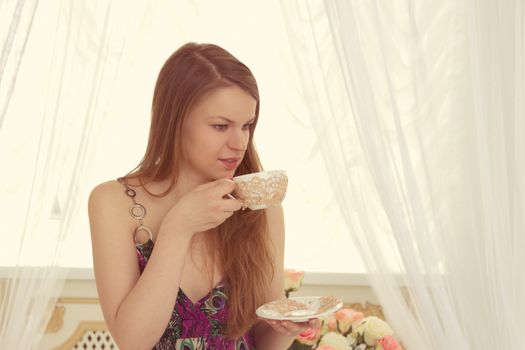 Woman drinking coffee at home with sunrise streaming in through window