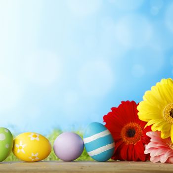 Colourful traditional Easter eggs arranged with colourful Gerbera daisies