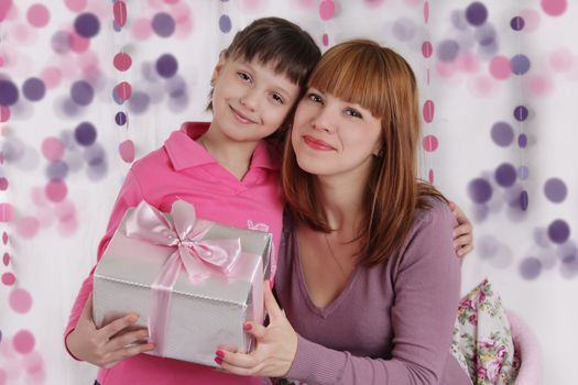Loving mother and daughter with present in pink decoration