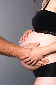 Pregnant woman standing touches belly with man