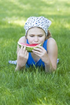 cute little girl eating watermelon on the grass