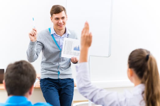 young teacher man talking with students in the classroom