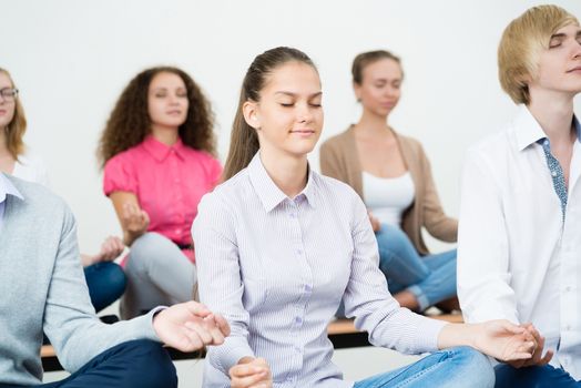 group of young people meditating in office at desk, group meditation