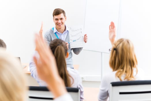 young teacher man talking with students in the classroom