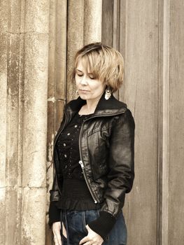 woman looking thoughful leaning against stone pillar
