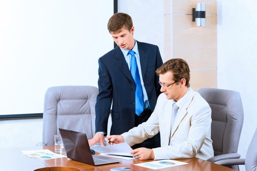 Business people talking, sitting at the table, watching the presentation on a laptop