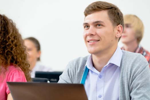 Portrait of a young student in the classroom, working with a laptop