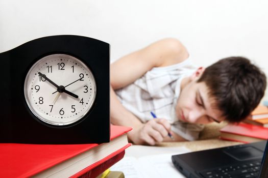 Teenager preparing for Exam in the Night at the Home. Focus on the Clock
