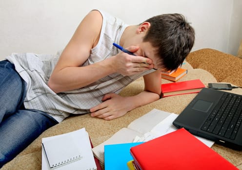 Tired Teenager preparing for Exam on the Sofa at the Home