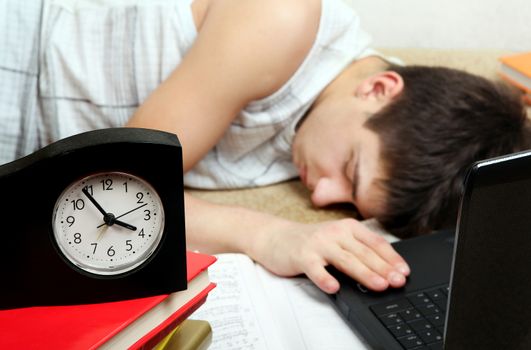 Teenager sleeping after prepare for Exam at the Home. Focus on the Clock