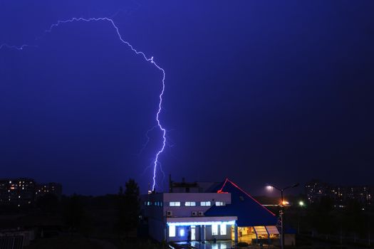 Severe lightning storm with rain over a city buildings at night