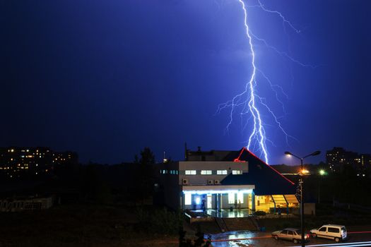 Severe lightning storm with rain over a city buildings at night