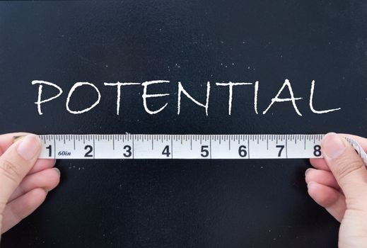 Tape measurement of the word potential on a chalkboard 