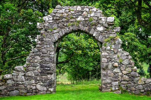 Old stone entrance wall in green landscaped garden