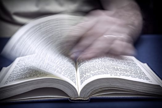 Man turns the page in an old little bible or book