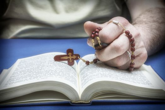 Christian believer praying to God with rosary in hand