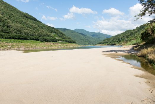 River bed landscape in South Korea with sandbank and green mountains