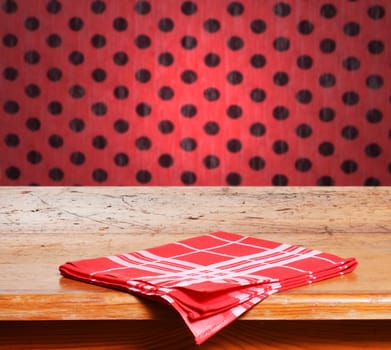 Empty wooden table and defocused red wall with black dots