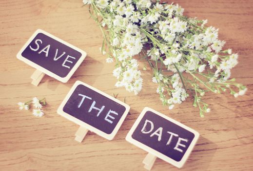Save the date written on blackboard with flower, retro filter effect